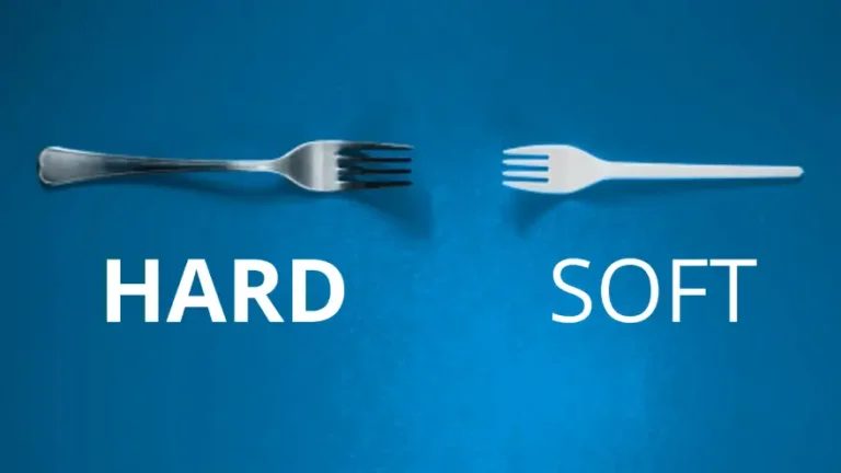 Two forks laying on a blue background. One metal fork with the word HARD underneath. The other fork is plastic and has the word SOFT underneath.